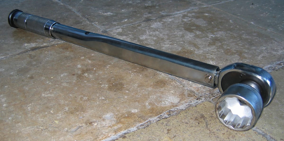 A micrometer click-type torque wrench with a twelve-point socket fitted, the knurled adjustment collar visible at the handle end